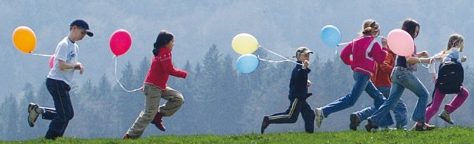 A group children with balloons running on a hill.